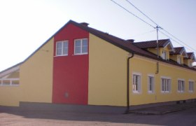 Außenansicht, © © Bianca Waysmayer Außenansicht eines gelb-roten Gebäudes mit mehreren Fenstern und einem Satteldach.