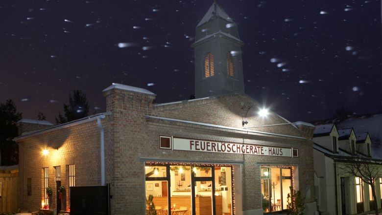 Alte Feuerwehr, © MG Bad Fischau-Brunn, Foto: Lukas Dostal Altes Feuerwehrhaus bei Nacht mit Lichtern und Schneefall.