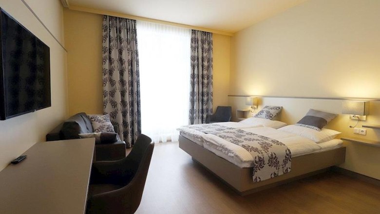 Kirchenwirt - Hotel - DZ Sonnwendstein, © Karin Stranz Modern eingerichtetes Hotelzimmer mit Doppelbett, Schreibtisch, Fernseher und Sesseln.