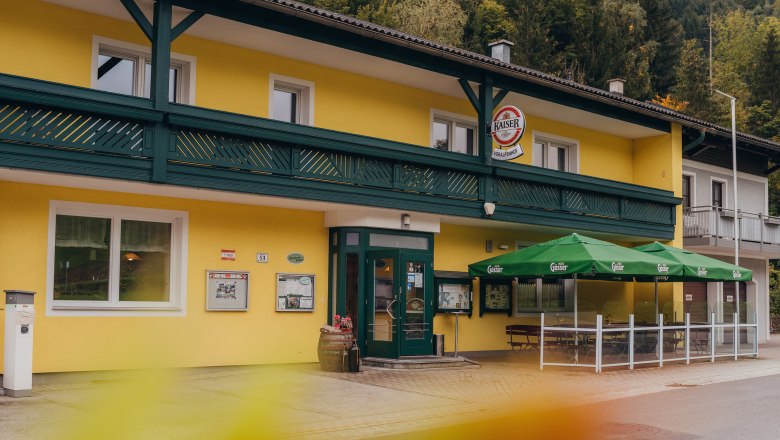 Wirtshaus mit hauseigenem Klein-Wasserkraftwerk, © Niederösterreich Werbung/Daniela Führer Gelbes Wirtshaus mit grünen Markisen und Schildern, umgeben von Bäumen.