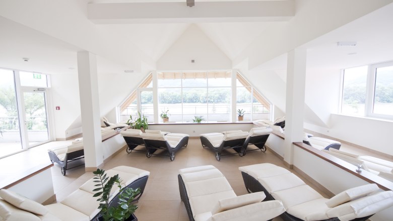 Penthouse_Spa_Liegelandschaft, © Alexander Pfeffel Heller Spa-Raum mit Liegestühlen und großen Fenstern.