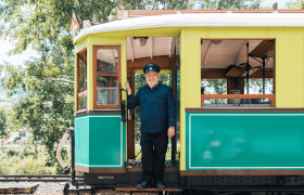 Höllentalbahn, © Österreich Werbung/Stefan Strasser Ein Zugführer in Uniform steht lächelnd in der Tür eines historischen Zuges.