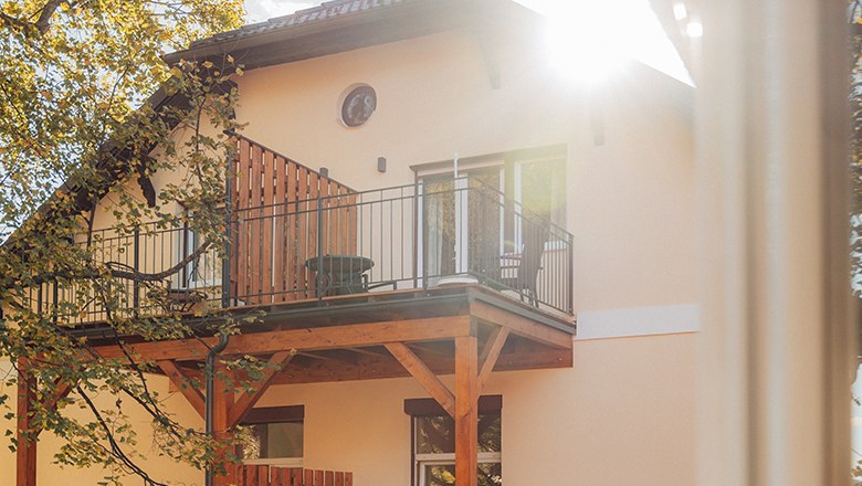 Payerbacherhof, © Payerbacherhof - Christopher Tarkus Haus mit Balkon und Sonnenschein durch Bäume.