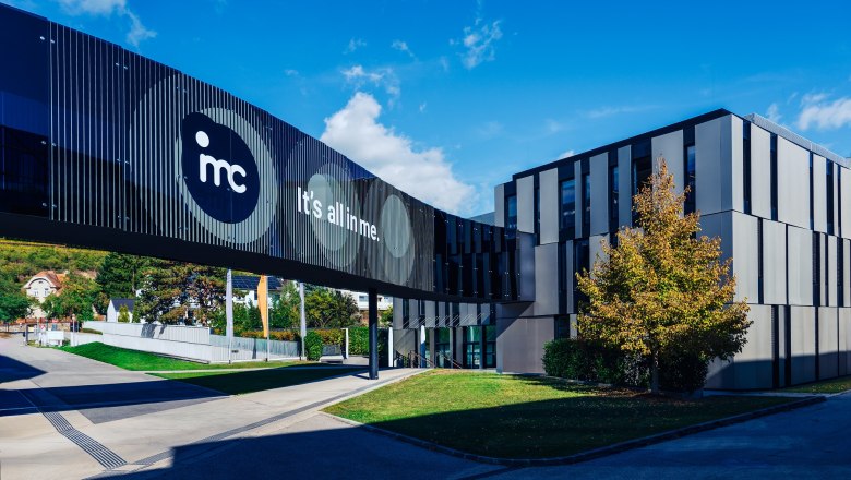 IMC Krems, © IMC Krems/Lukas Bezila Modernes Gebäude der IMC Krems mit Glasbrücke und Schriftzug 'It's all in me'.