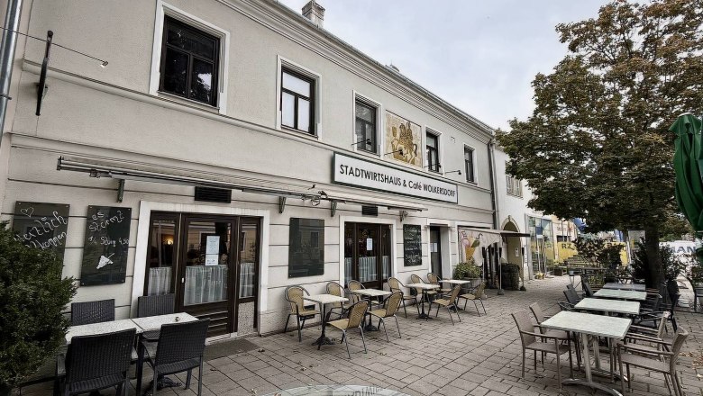 Stadtwirtshaus & Cafe Wolkersdorf, © Stadtwirtshaus & Cafe Wolkersdorf Außenansicht eines Cafés mit Tischen und Stühlen auf dem Gehweg.