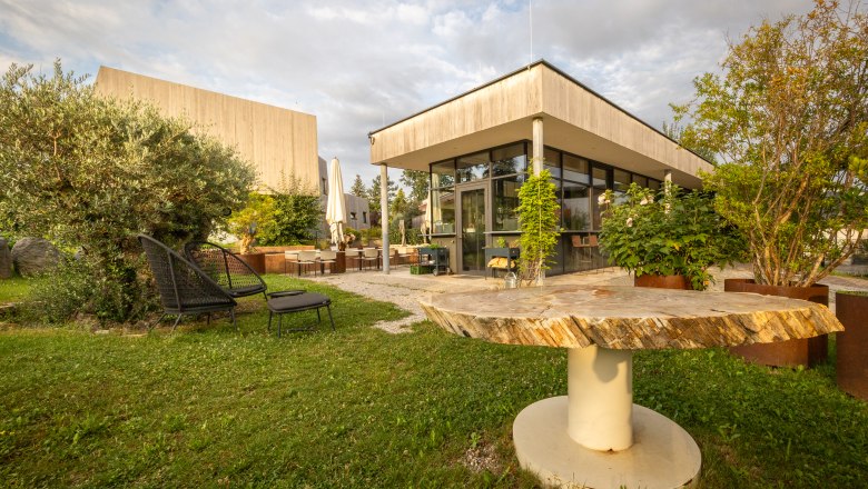 Naturhotel Gut Guntrams Gartenlofts, © Niederösterreich Werbung / Maximilian Pawlikowsky Gartenbereich eines modernen Hotels mit Sitzgelegenheiten und Pflanzen.