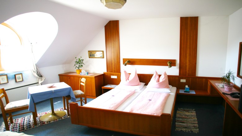 Gasthof-Pension "Drei Hacken", © Gasthof "Drei Hacken" Gemütliches Hotelzimmer mit Doppelbett, Holzmöbeln und Tisch mit Stühlen.
