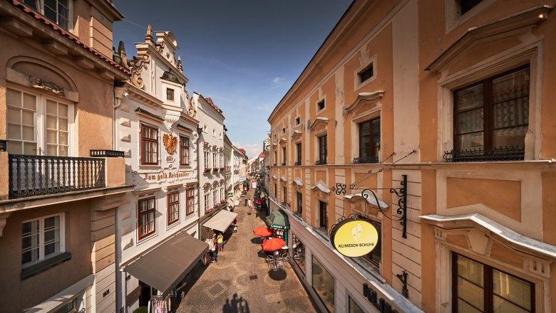 Altstadt von Krems, © Andreas Hofer Blick auf eine historische Straße in der Altstadt von Krems mit alten Gebäuden und Geschäften.