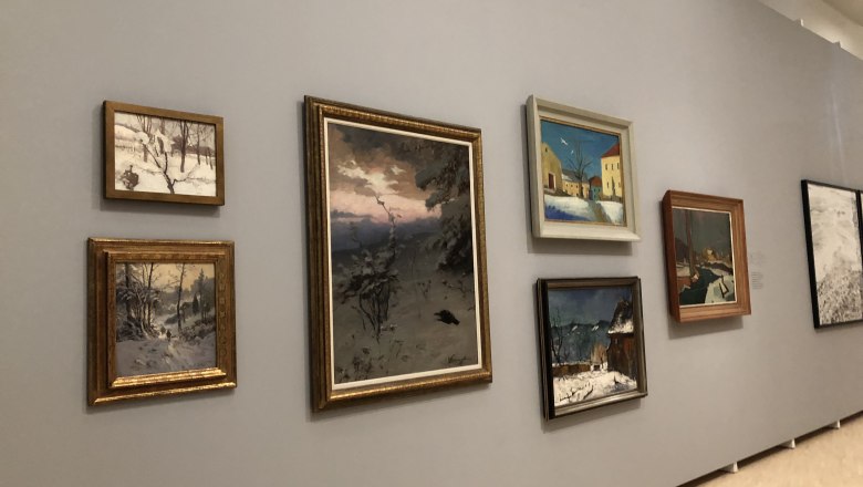 Ausstellung in der Landesgalerie, © Donau NÖ Tourismus/JS Eine Wand in einer Galerie mit mehreren Gemälden, die Winterlandschaften zeigen.