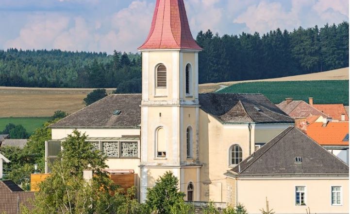 Pfarrkirche Hochwolkersdorf, © Walter Strobl, www.audivision.at Pfarrkirche Hochwolkersdorf mit rotem, spitzen Turmdach und umliegender Landschaft.