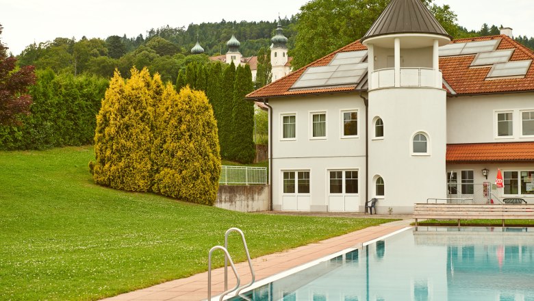 Freizeitanlage Artstetten, © Klaus Engelmayer Außenansicht einer Freizeitanlage mit Pool und Gebäude, im Hintergrund Bäume und Kirchtürme.