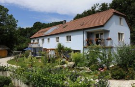 Gästehaus Langthaler Aussenansicht, © Gästehaus Langthaler Außenansicht eines blauen Gästehauses mit Garten und Spielplatz.