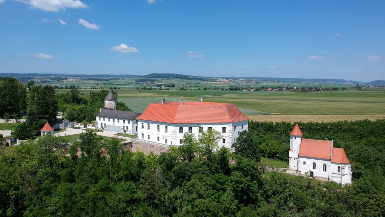 Schloss Viehofen, © Sabine Figl, Schloss Viehofen Luftaufnahme von Schloss Viehofen mit rotem Dach, umgeben von grüner Landschaft und Feldern.