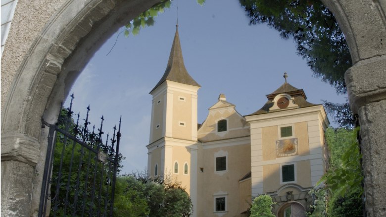 SchlossMühlbach, © Gemeinde Hohenwarth-Mühlbach a.M. Schloss Mühlbach hinter einem steinernen Torbogen mit schmiedeeisernem Tor.