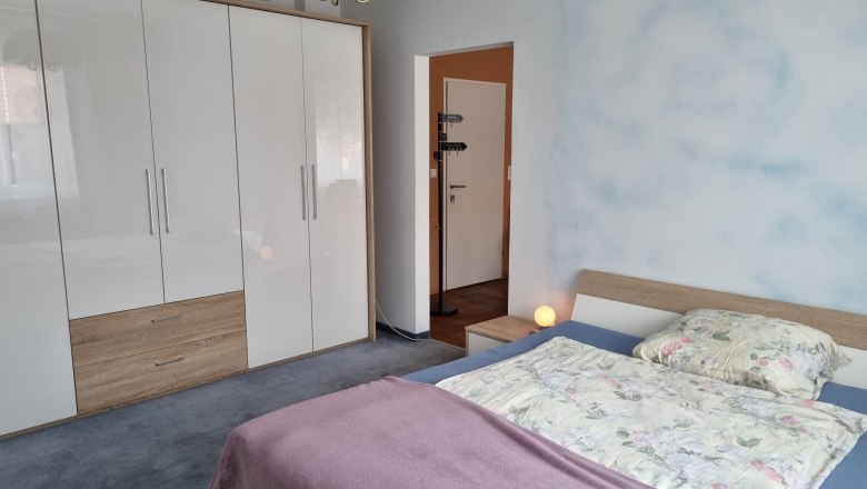 Doppelzimmer, © Wolfgang Greil Ein Schlafzimmer mit einem Doppelbett, einem großen weißen Kleiderschrank und einer Nachttischlampe.