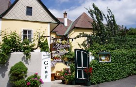 Aussenansicht, © Familie Graf Außenansicht eines gelben Gebäudes mit Pflanzen und Blumen.