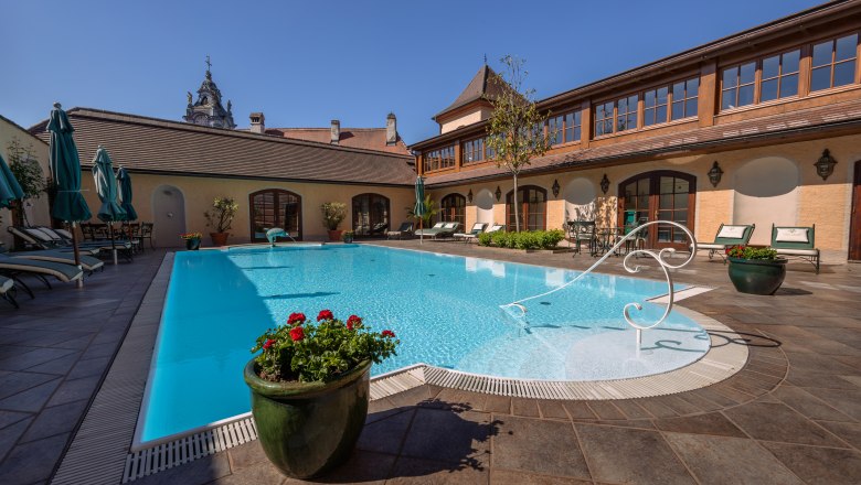 Hotel Schloss Dürnstein, © Niederösterreich Werbung / Maximilian Pawlikowsky Außenpool des Hotel Schloss Dürnstein mit Liegestühlen und Sonnenschirmen.