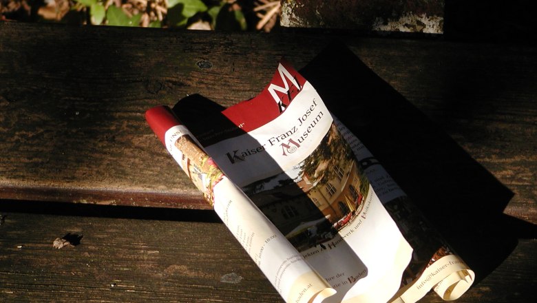 Kaiser-Franz-Josef-Museum, © Kaiser Franz Museum Zusammengerolltes Prospekt des Kaiser-Franz-Josef-Museums auf einer Holzbank.