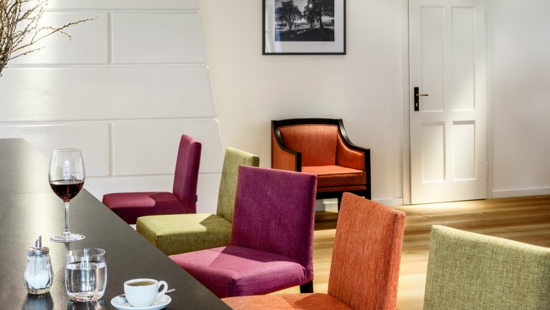 Hotel zum Glockenturm, © croce&wir Innenansicht eines modernen Hotel-Lounges mit bunten Stühlen, einem Tisch mit Getränken und einem Bild an der Wand.