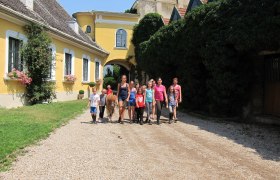 Paradise für Kinder, Jugendliche und Erwachsene, © rgf Gruppe von Kindern und Erwachsenen mit Pony vor gelbem Gebäude.