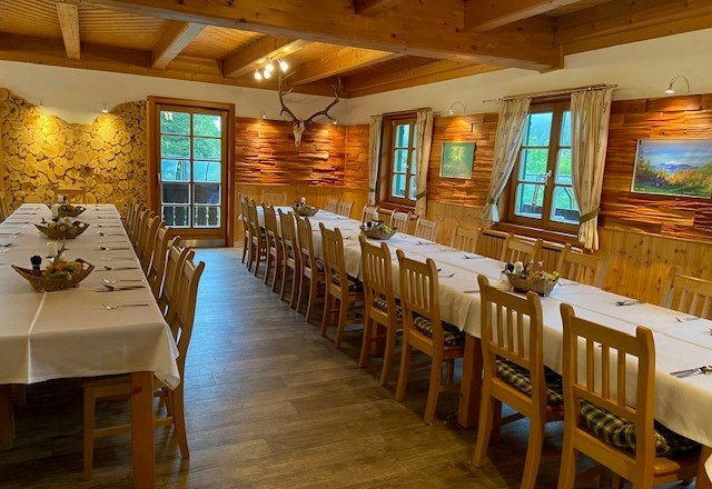 Ansprechender Speisesaal für diverse Feiern, © Wiener Alpen Rustikaler Speisesaal mit langen, gedeckten Tischen und Holzwänden.