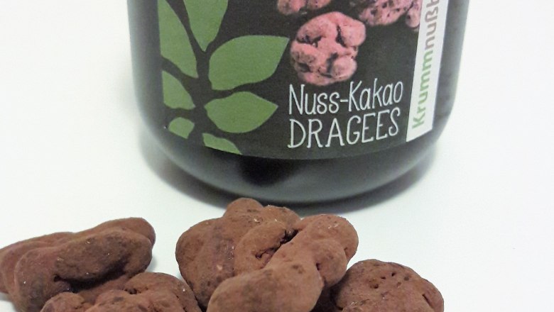 12-nuss-kakao-dragees, © Johann Peham Ein Glas mit der Aufschrift 'Nuss-Kakao Dragees' und einige Dragees davor.