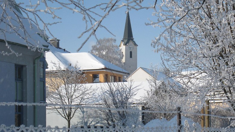Winterimpression, © Gemeinde St. Margarethen Verschneite Dorfansicht mit Kirche und Bäumen im Winter.