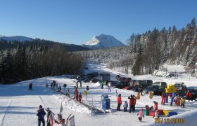 Lifte in Puchenstuben, © Schilifte Puchenstuben GesmbH & Co KG Winterlandschaft mit Skilift und spielenden Kindern in Puchenstuben.