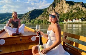 Ankerplatz Wachau auf Tour, © Ankerplatz Wachau Zwei Frauen auf einem Boot in der Wachau, genießen Wein mit Blick auf die Berge.