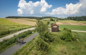 Thayarunde, Radfahren, © Waldviertel Tourismus, Erwin Haiden Die sanften Hügel und weitläufigen Felder laden zu einer erfrischenden Radtour ein. Radfahrer genießen die idyllische Landschaft, während die Sonne über den Horizont strahlt und die Wolken sanft am Himmel treiben. Ein perfekter Tag, um die Natur in ihrer vollen Pracht zu erleben.