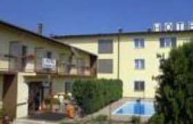 Hotel Rumpler, © Hotel Rumpler Außenansicht eines gelben Hotels mit Pool und Garten.