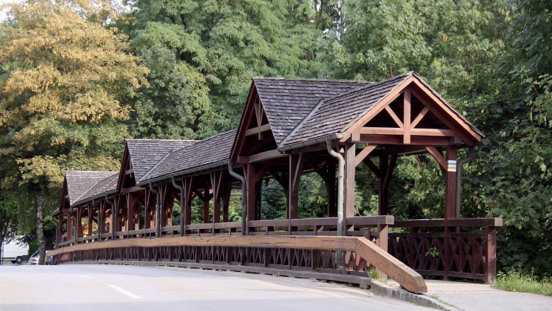 Leithabrücke Katzelsdorf, © Steindy, CC BY-SA 3.0 Holzbrücke mit überdachtem Gehweg in einer grünen Umgebung.