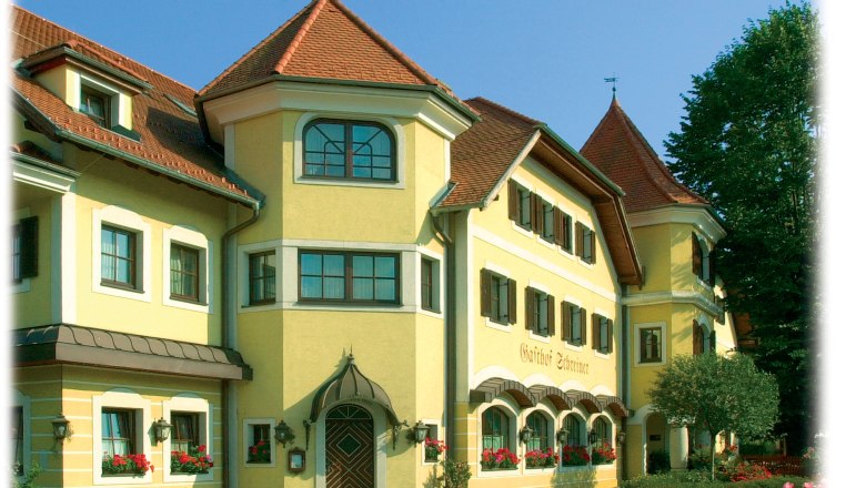 Schreiners – das Waldviertel Haus, © Schreiners – das Waldviertel Haus Gelbes Gebäude mit roten Dächern und vielen Fenstern, umgeben von Bäumen.