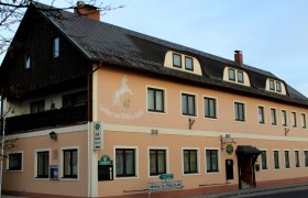 Gasthof „Zum weißen Rössel“, © Gasthof „Zum weißen Rössel“ Außenansicht des Gasthofs 'Zum weißen Rössel' mit beige Fassade und Pferdemalerei.