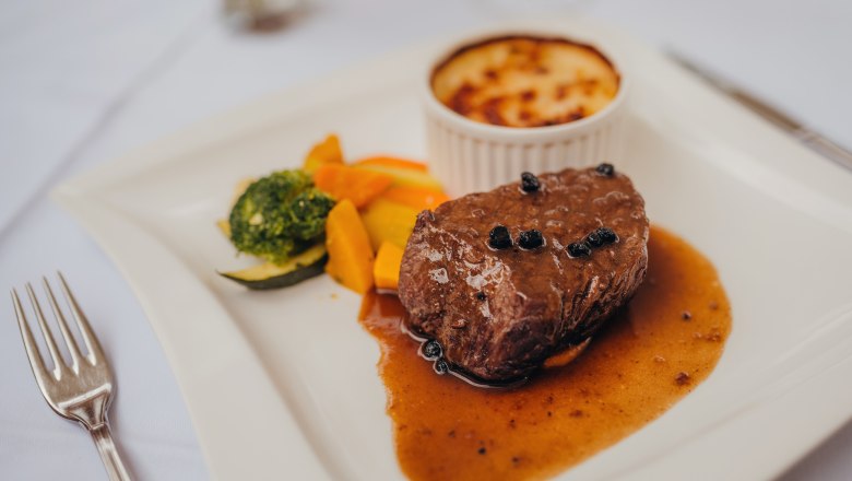 Pfeffersteak, © Niederösterreich Werbung/Daniela Führer Ein Pfeffersteak mit Sauce, Gemüse und Kartoffelgratin auf einem weißen Teller.
