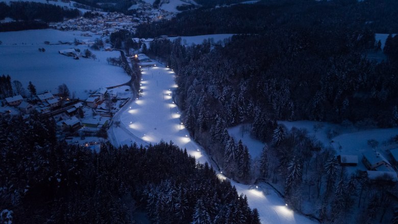 Flutlichtloipe in Zöbern, © Wiener Alpen, Martin Fülöp Luftaufnahme einer beleuchteten Langlaufloipe in einer verschneiten Landschaft bei Nacht.