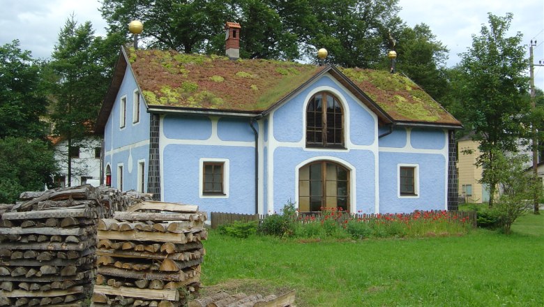 Dorfmuseum Roiten, © Rauch Blaues Haus mit Grasdach und Holzstapeln im Vordergrund.