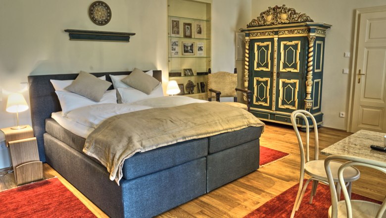 Suite Ruediger in der Villa Tranquillini, © Herbert Lehmann Elegantes Schlafzimmer mit Doppelbett, antikem Schrank und roten Teppichen.