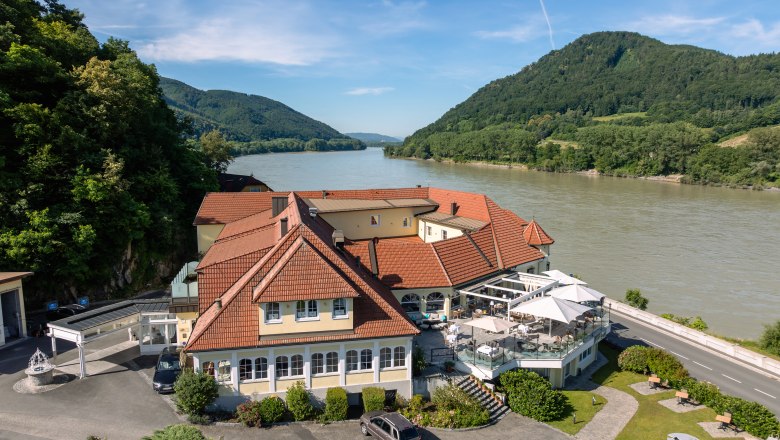 Hotel ResidenzWachau, © Niederösterreich Werbung / Maximilian Pawlikowsky Hotel ResidenzWachau am Flussufer mit umliegenden Hügeln.