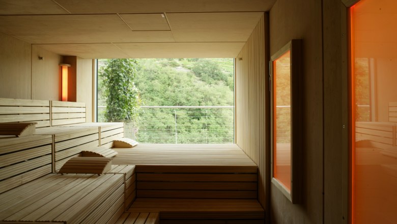 Sauna, © Steigenberger Hotel and Spa, Andreas Hofer Innenansicht einer modernen Sauna mit Holzbänken und großem Fenster mit Blick auf grüne Landschaft.