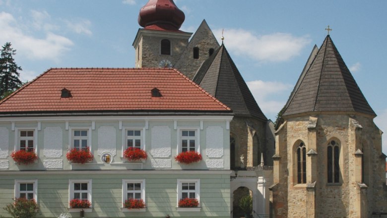 Marktplatz Maria-Anzbach, © Maria-Anzbach Historisches Gebäude mit rotem Dach und Kirche im Hintergrund auf dem Marktplatz Maria-Anzbach.