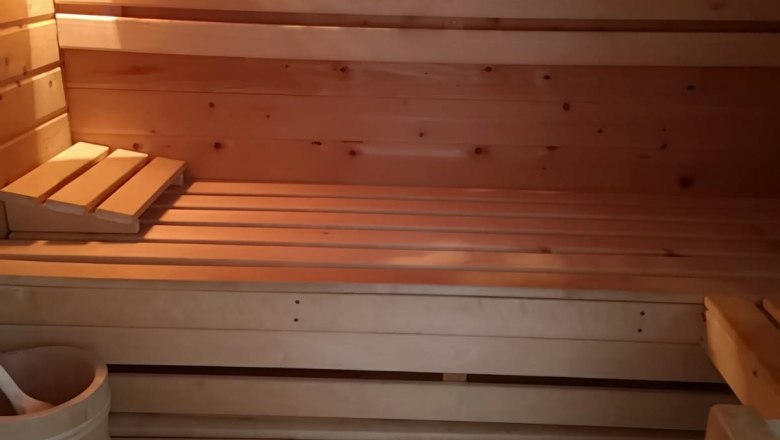 Sauna, © Haselberger Innenansicht einer Holzsauna mit Bänken, Thermometer und Eimer.