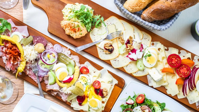 Heurigenjause im Weingut Stadler, © Robert Herbst Verschiedene Aufschnitt- und Käseplatten mit Brot und Salat auf einem Tisch.