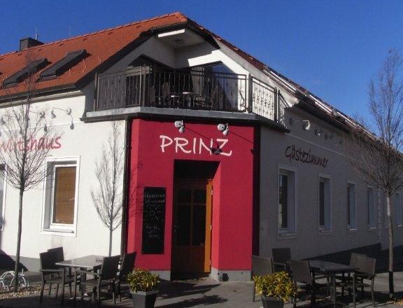 Aussenansicht, © GH Prinz Außenansicht eines Gebäudes mit der Aufschrift 'Prinz', Gastgarten mit Tischen und Stühlen, blauer Himmel.