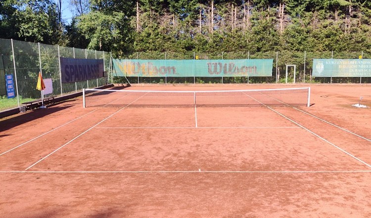 Tennis Bad Schönau, © Wiener Alpen Ein leerer Tennisplatz mit rotem Sandbelag und umliegenden Bäumen.
