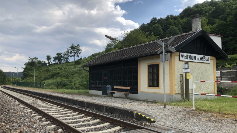 Bahnhof Willendorf, © Donau NÖ Tourismus Kleiner Bahnhof in ländlicher Umgebung mit Gleisen und einem Wartehäuschen.