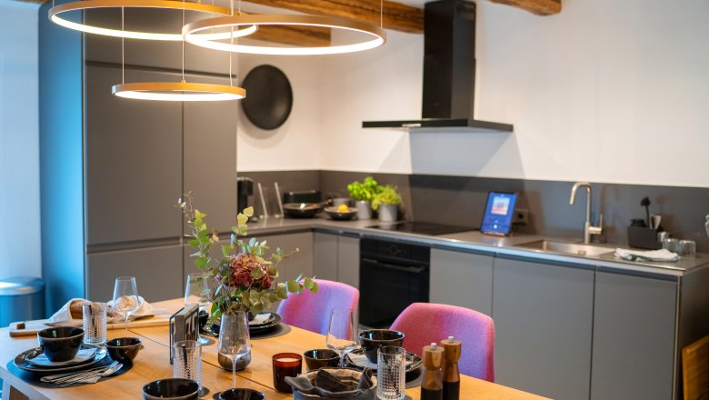 Chalet´s & Plätze voller WUNDER - Weidehaus De Luxe, © WUNDERVOLL eben Moderne Küche mit Esstisch, gedeckt für vier Personen, und stilvoller Beleuchtung.