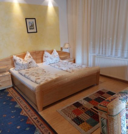 Gästezimmer Weixelbaum, © Familie Weixelbaum Gemütliches Gästezimmer mit Doppelbett, bunten Teppichen und Holzmöbeln.