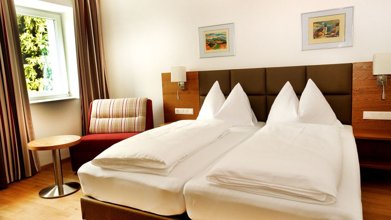 Zimmer, © Crepaz Ein modernes Hotelzimmer mit Doppelbett, Sessel, kleinem Tisch und zwei Bildern an der Wand.