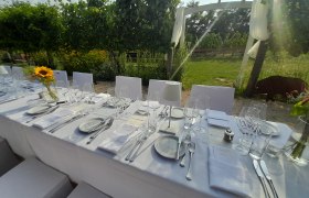 Tafeln im Weinviertel, © Weinviertel Tourismus GmbH Elegante, gedeckte Tafel im Freien mit weißen Tischdecken und Sonnenblumen in einem Garten.
